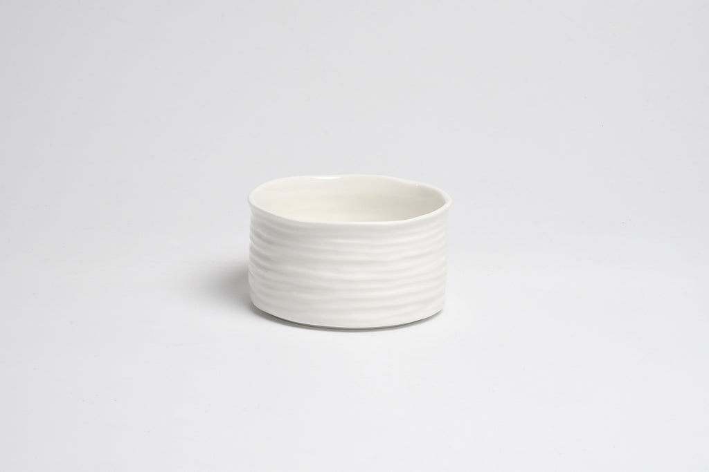 White ceramic bowl with ribbed texture on a light gray background