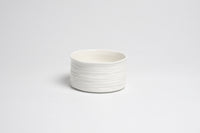 White ceramic bowl with ribbed texture on a light gray background