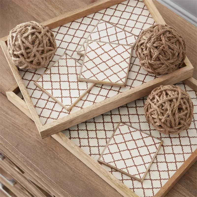 Decorative coasters with geometric pattern on a wooden tray with 4 inch natural tan seagrass balls.