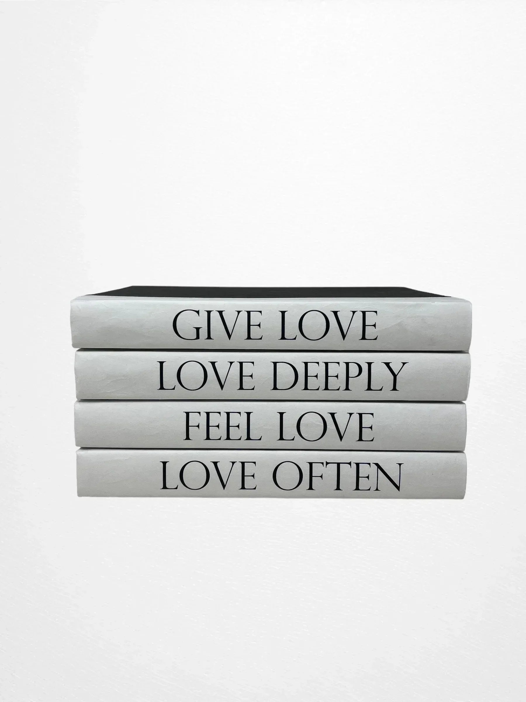 Stack of books with motivational phrases on a white background Four-volume decorative book set with spines reading Give Love, Love Deeply, Feel Love, and Love Often