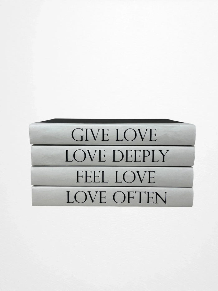Stack of books with motivational phrases on a white background Four-volume decorative book set with spines reading Give Love, Love Deeply, Feel Love, and Love Often