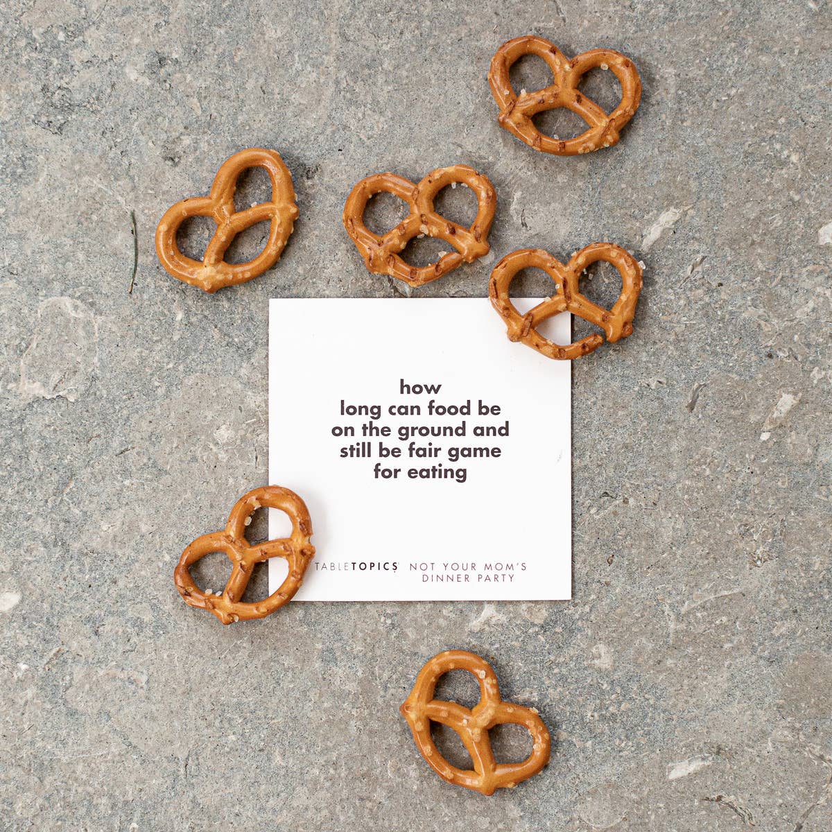 Pretzels scattered on a concrete surface with a card in the center.
