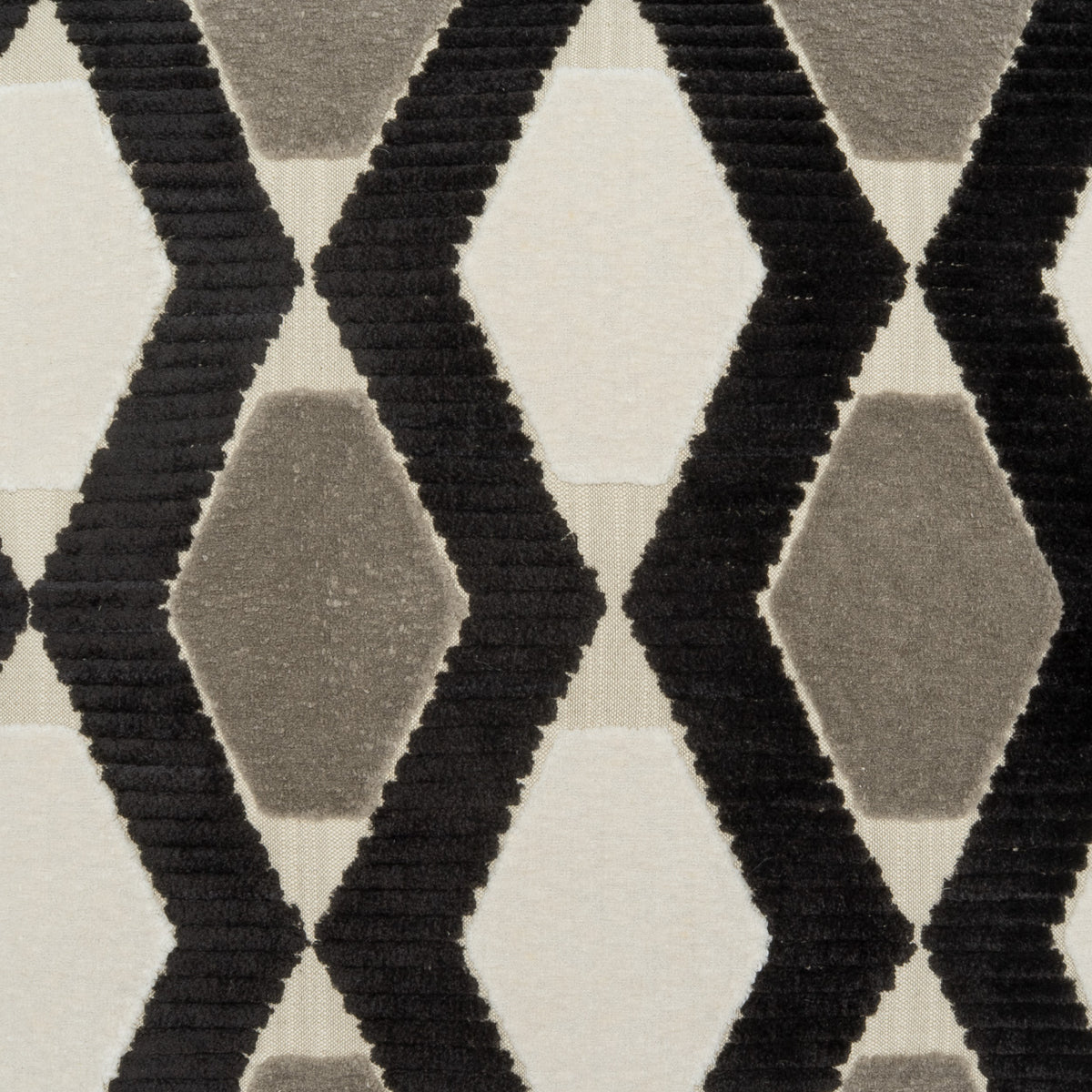 A close-up of a textured rug or fabric featuring a geometric pattern of black and gray diamonds on a warm off-white background.