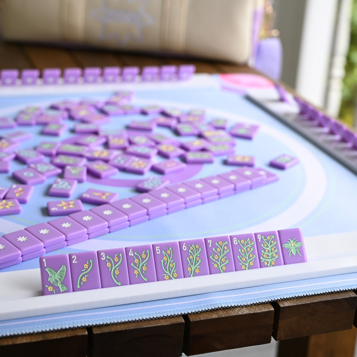 Purple mahjong tiles with floral designs on a white board.