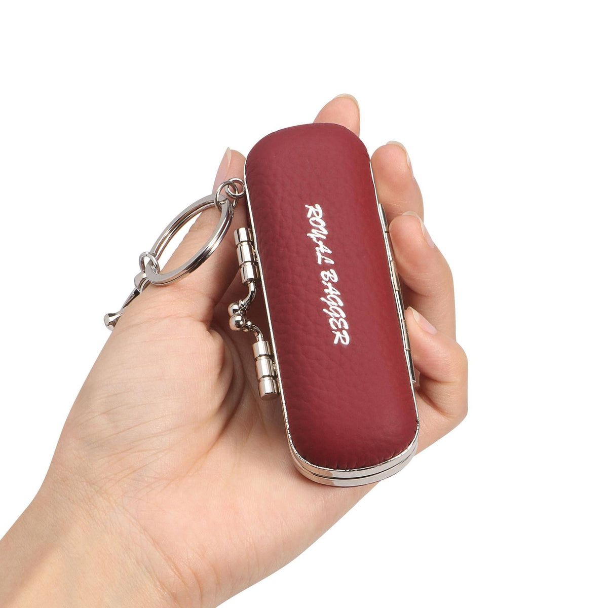 A hand holding a small burgundy leatherette key case with silver metal hinges and a key ring. The case has 'ROYAL BARGAZZ' printed vertically in white on the front.