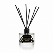 A reed diffuser bottle with clear glass, black reeds, and a black label reading 'Voyage by Ode Orange Blossom Barcelona' on a white background.