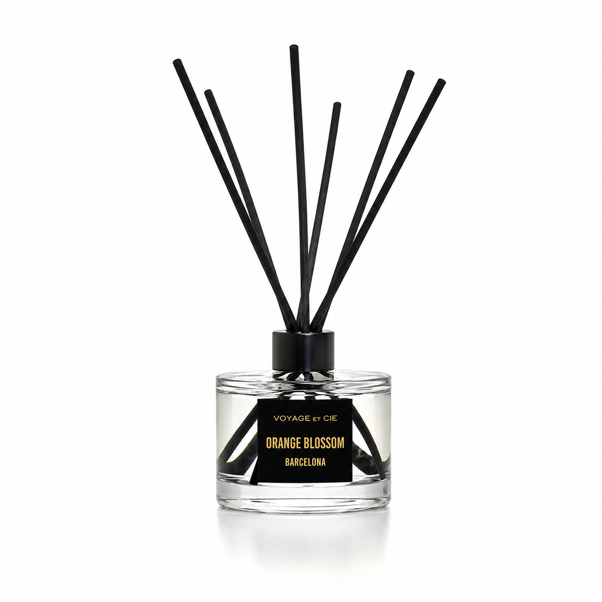 A reed diffuser bottle with clear glass, black reeds, and a black label reading 'Voyage by Ode Orange Blossom Barcelona' on a white background.