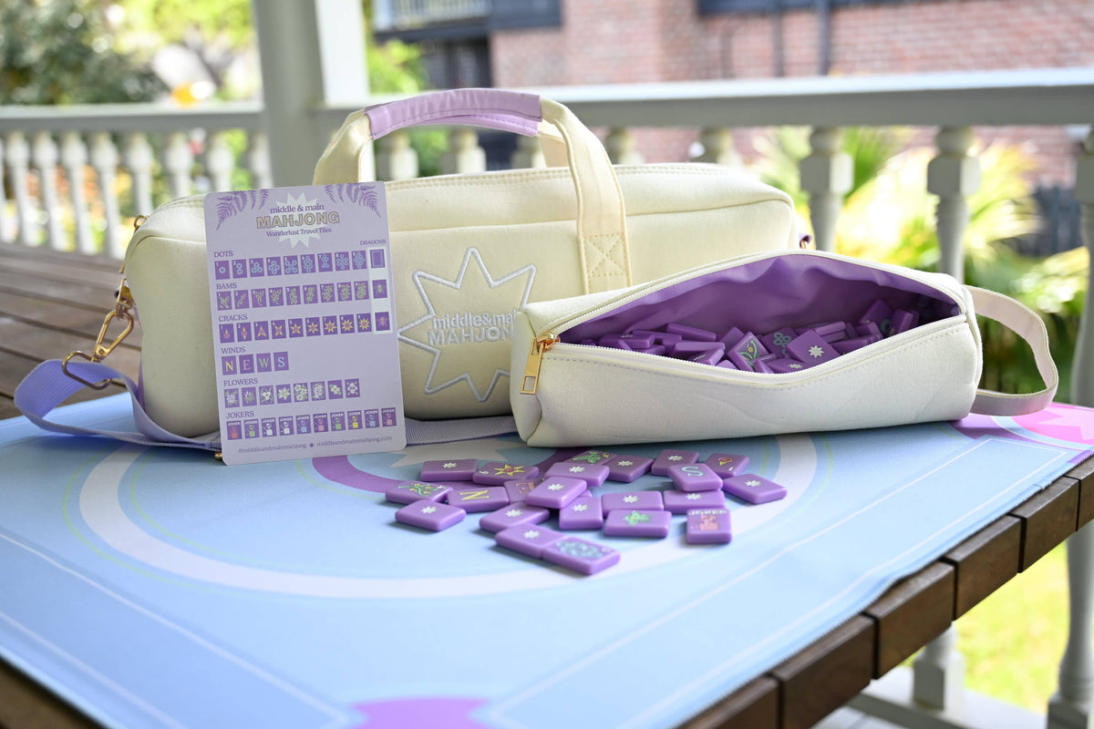 White and purple mahjong bags with purple items on a table outdoors