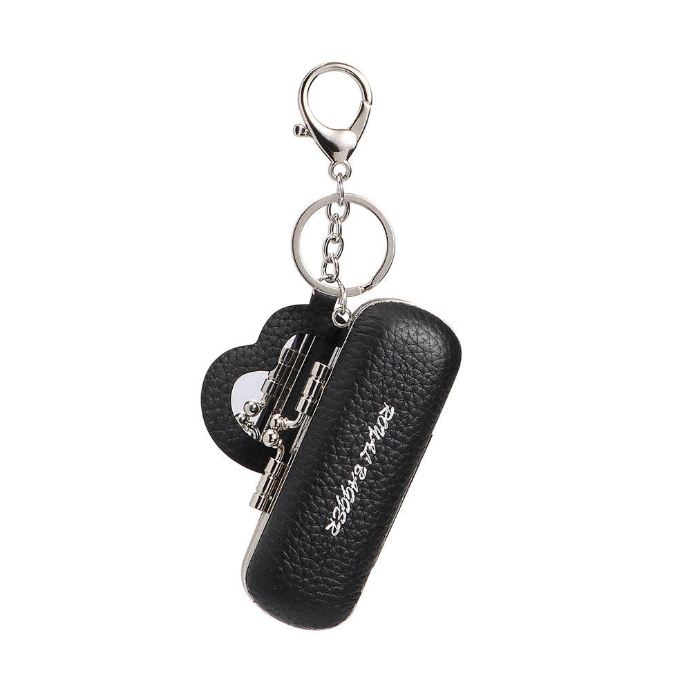 A dark green pebbled leather keychain case with a heart-shaped charm and silver-tone metal hardware, featuring the brand name 'saying right' in white script on the front.