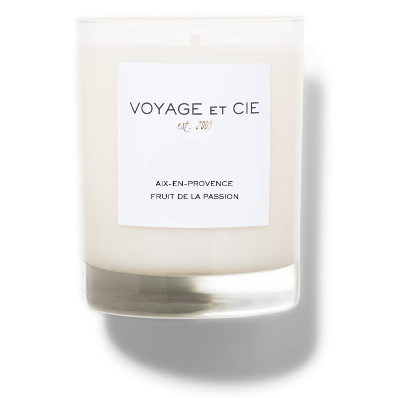 A clear glass jar candle with creamy off-white wax and a white rectangular label reading “VOYAGE ET CIE est. 202°°” and “LES ARRONDISSEMENTS 5ÉME QUARTIER LATIN SANTAL EPICER,” shown on a white background with a soft shadow.