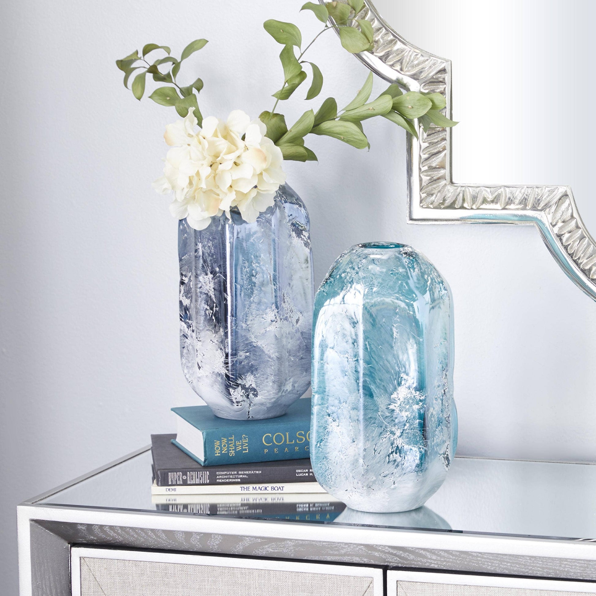 Decorative vases with flowers on a mirrored surface