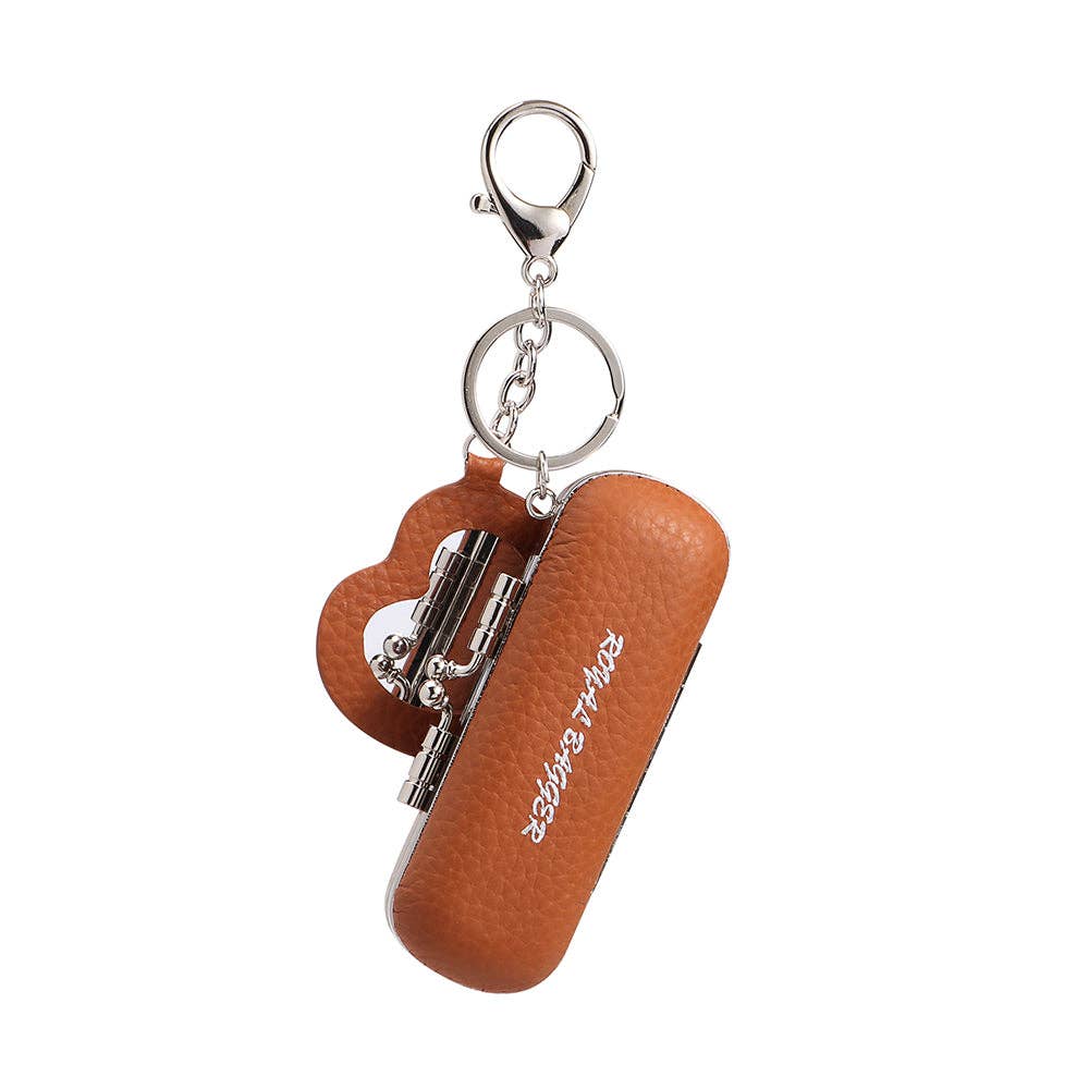 A miniature folding pocket saw keychain in textured brown faux leather with silver metal hardware, shown on a plain white background.