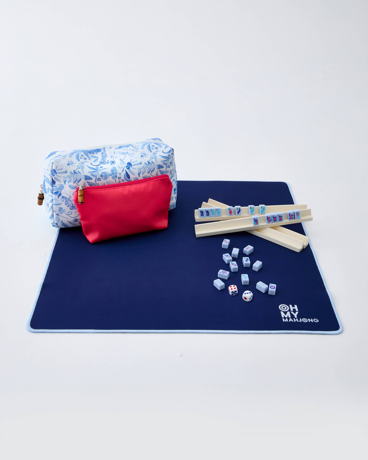 Mahjong set with tiles, dice, and carrying case on a blue mat.