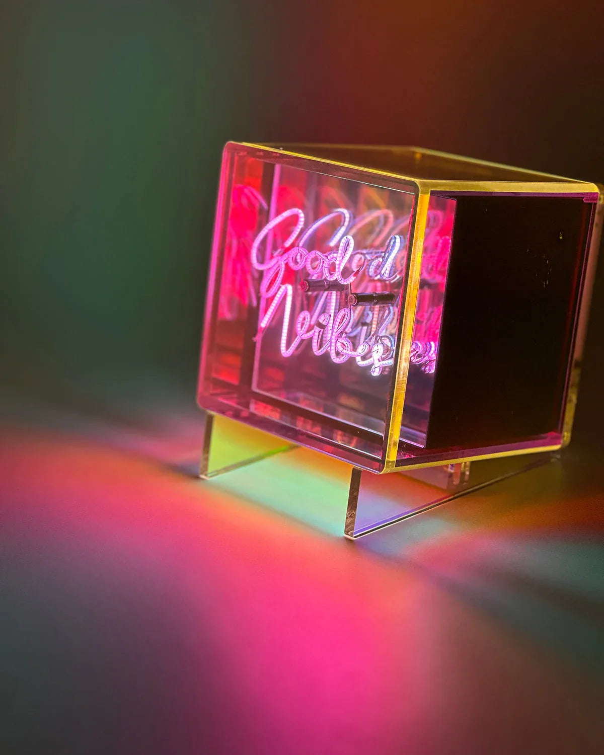 Neon sign with 'Good Vibes' text in a clear acrylic box on a dark background