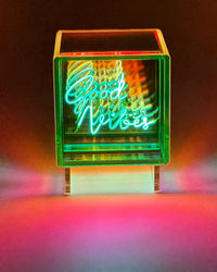 Neon sign with 'Good Vibes' text in a colorful box on a dark background