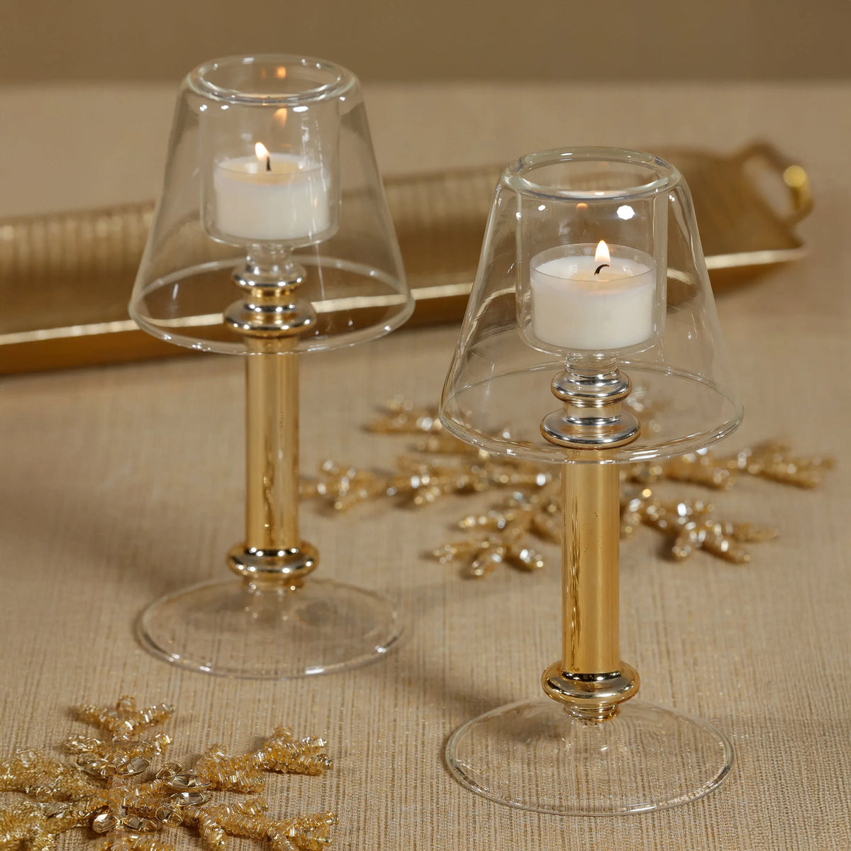 Two candle holders with candles on a textured surface with decorative elements.