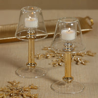 Two candle holders with candles on a textured surface with decorative elements.