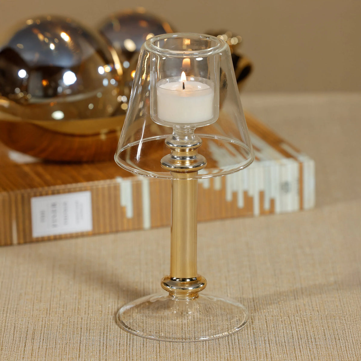 Clear glass candle holder with a white candle on a textured surface