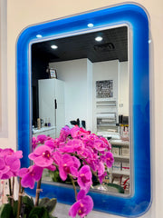 Blue-framed mirror with pink flowers in front