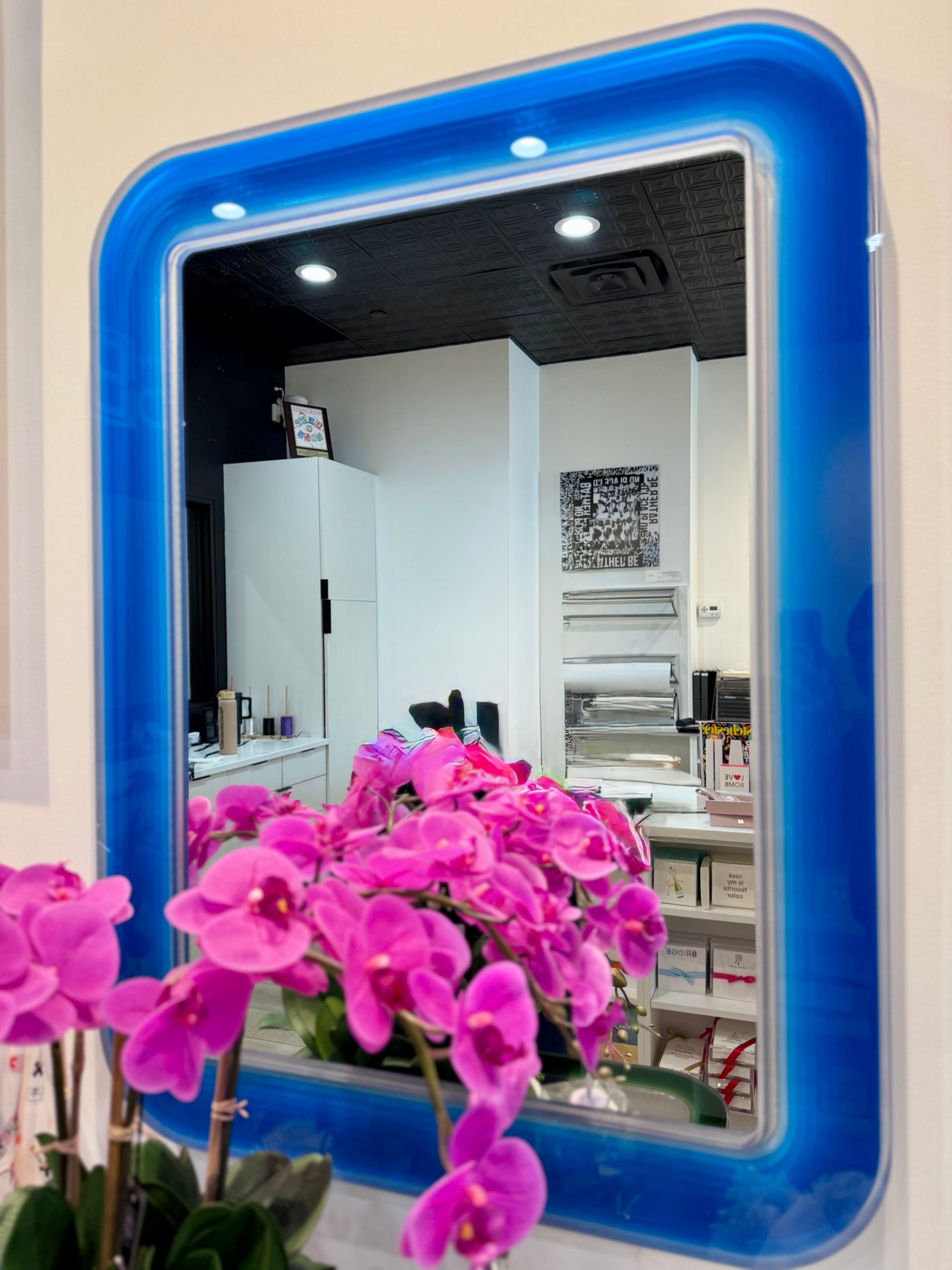 Blue-framed mirror with pink flowers in front