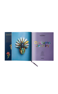 Open book showing a colorful brooch on a blue and purple page with 'Costume Jewelry' text. Costume Jewelry Patrizia Sandretto Re Rebaudengo collection book.