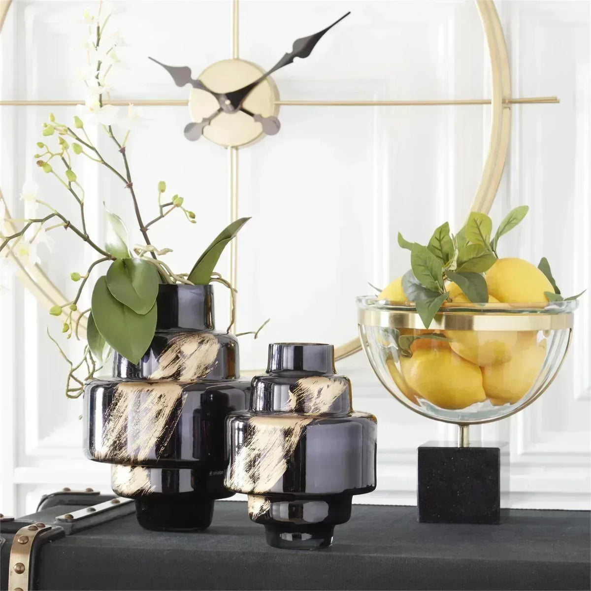 Decorative items including black and gold vases, a glass bowl with lemons, and a clock on a white wall.