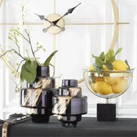 Decorative items including black and gold vases, a glass bowl with lemons, and a clock on a white wall.