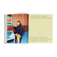 Open book with a photograph of a person in a room and text about Sir Elton John and David Furnish.