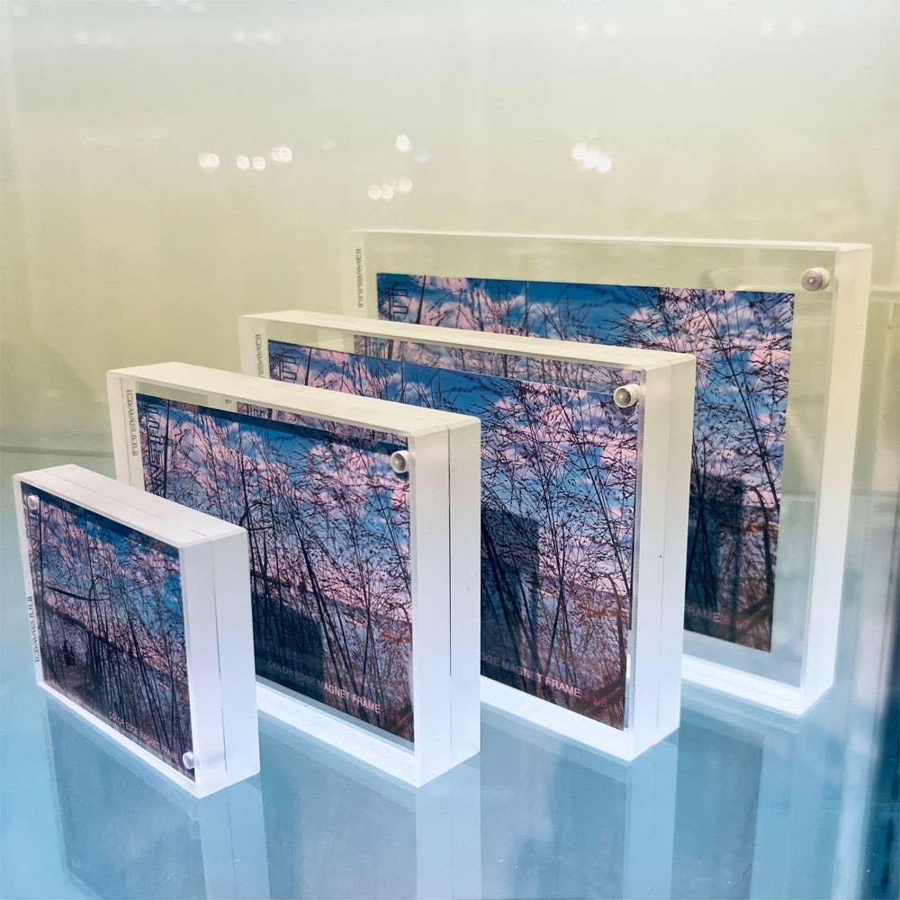 Set of three white photo frames with a nature scene on a reflective surface.