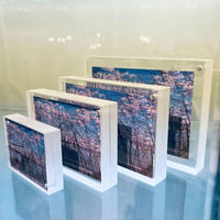 Set of three white photo frames with a nature scene on a reflective surface.