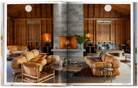 Open book showing a rustic living room with wooden walls, a fireplace, and brown furniture Luxury Ranch Decor & Mid-Century Modern Hotels
