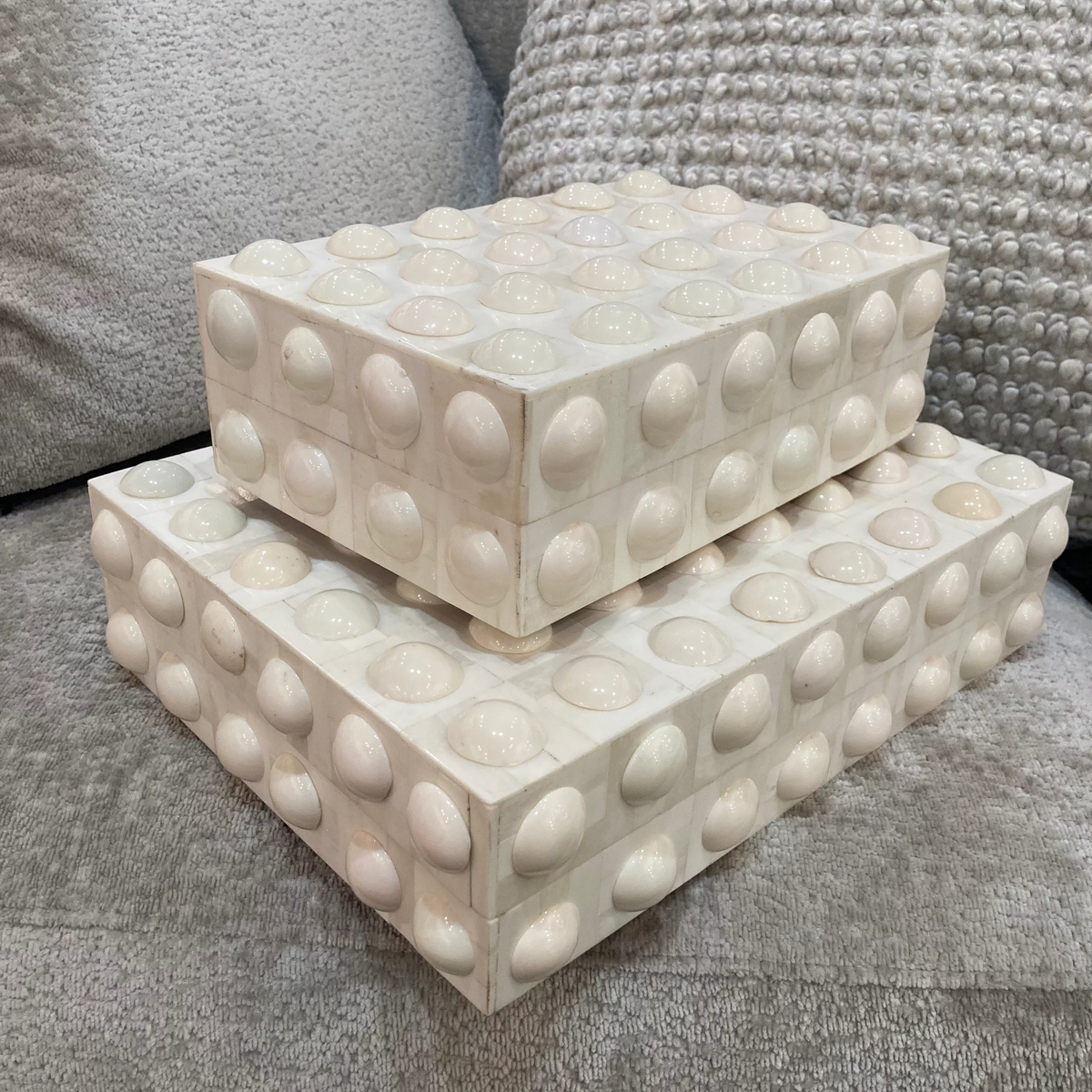 Two decorative boxes with a bubble texture on a gray surface.