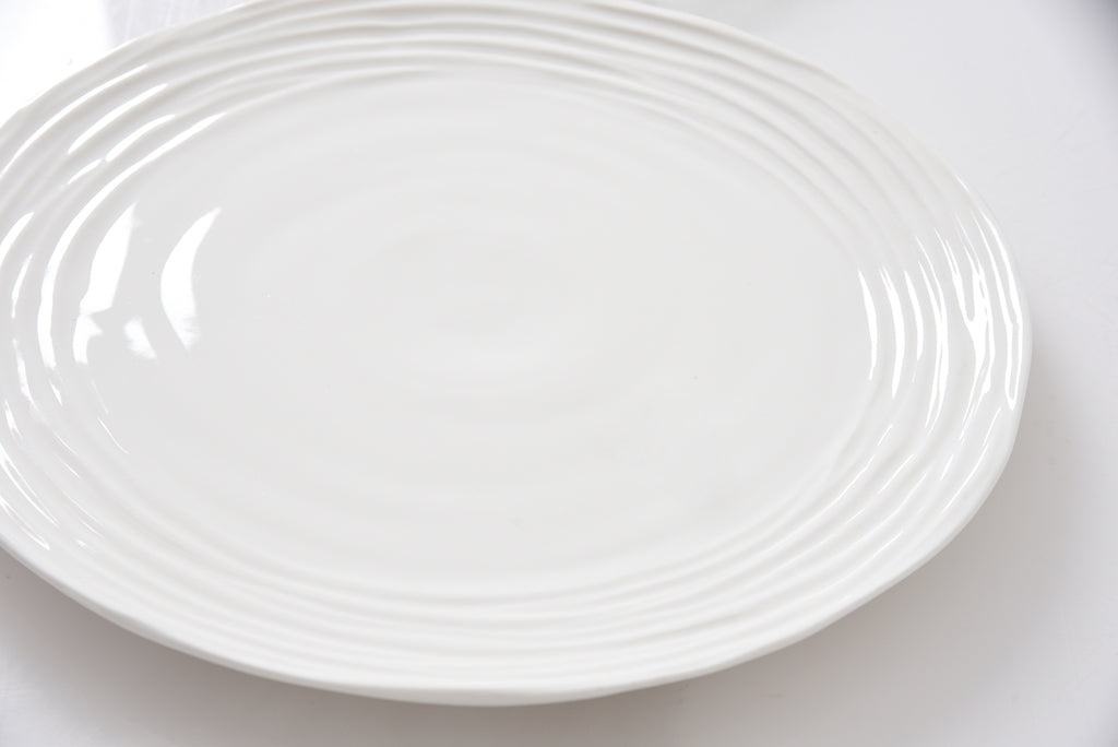 White ceramic plate with a textured rim on a white background