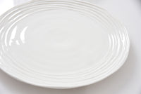 White ceramic plate with a textured rim on a white background