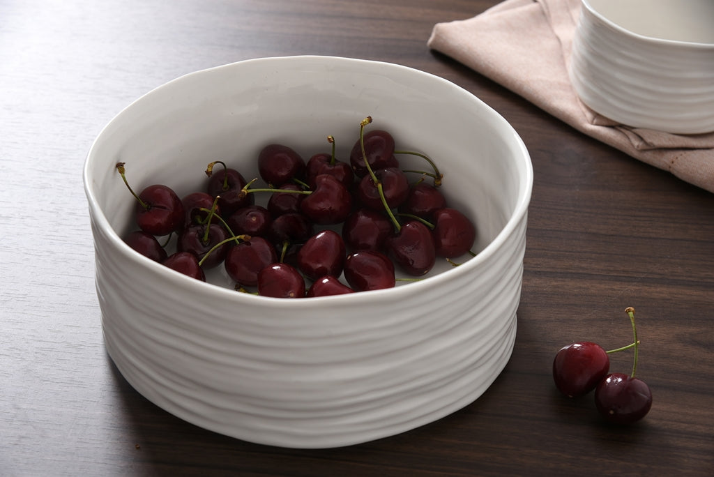 White bowl filled with cherries on a wooden table