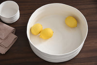White ceramic bowl with lemons on a wooden surface