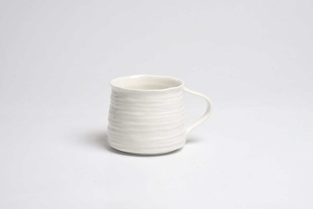 White ceramic mug with a textured design on a light gray background