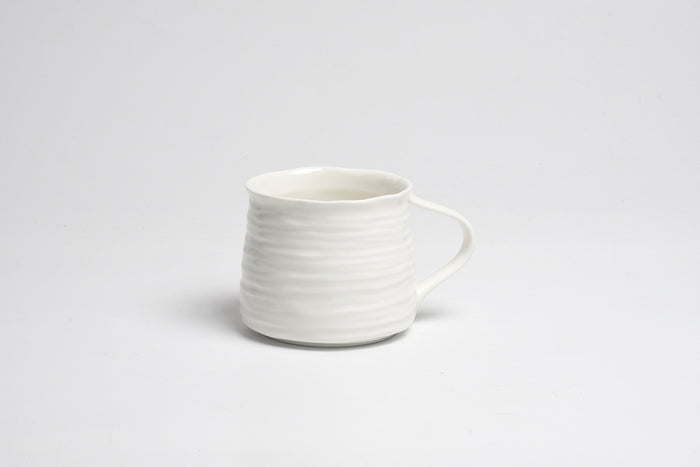 White ceramic mug with a textured design on a light gray background