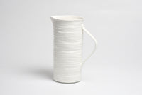 White ceramic pitcher on a light gray background