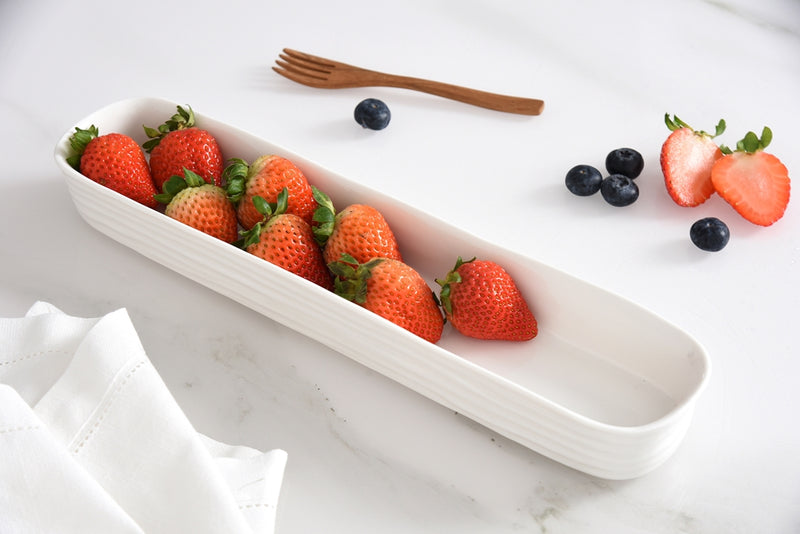 White ceramic dish with strawberries on a white surface