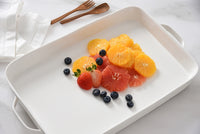 Fruit salad with oranges, grapefruits, and blueberries on a white tray.