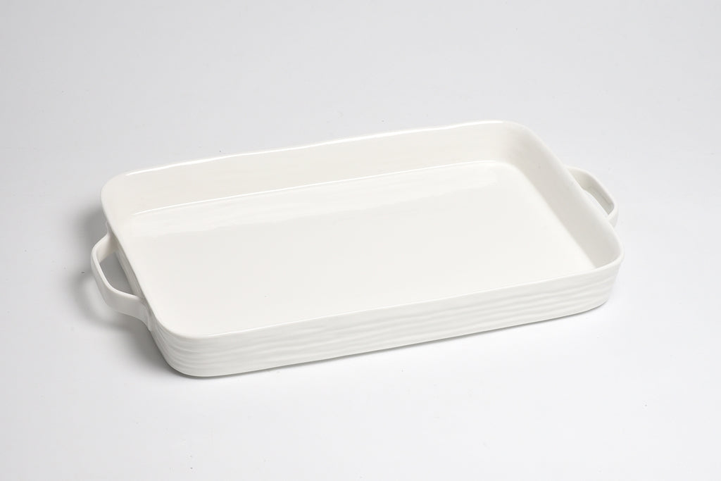 White ceramic baking dish with handles on a light gray background