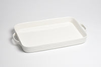 White ceramic baking dish with handles on a light gray background