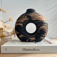 Decorative black brown vase with black and gold marbled pattern on a book