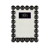 Black beaded frame with a white center on a white background, featuring the SBG logo.