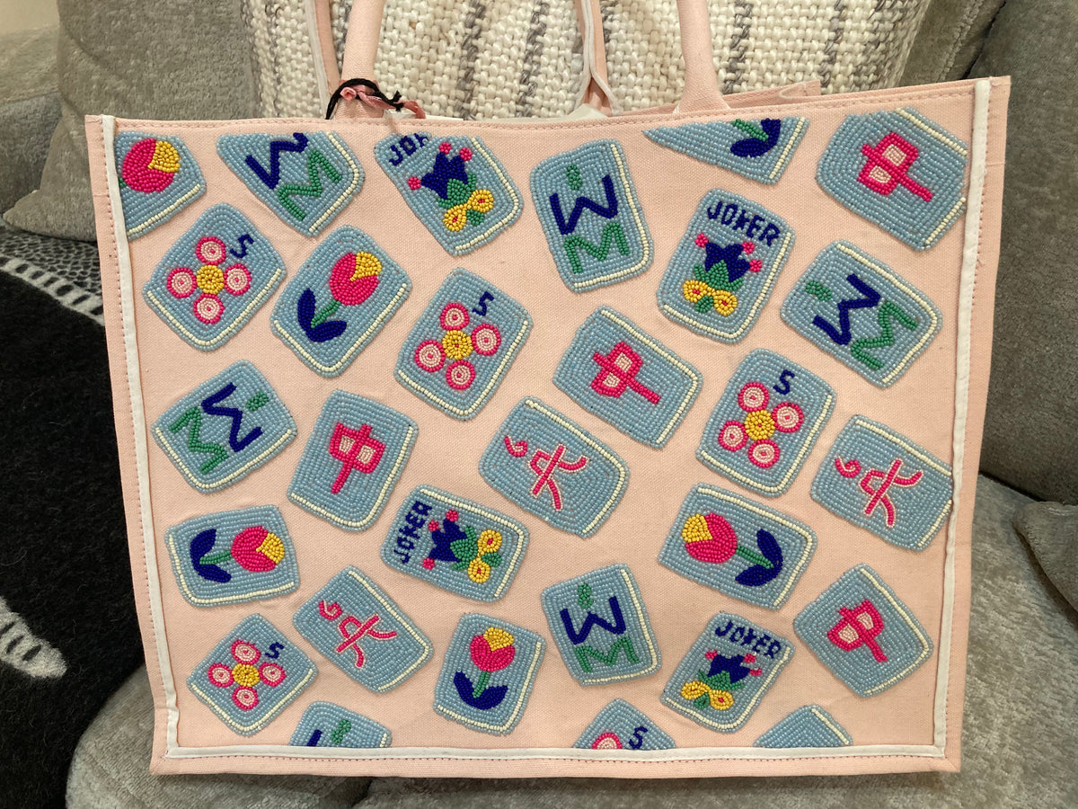 Pink bag with colorful embroidered patches featuring letters and symbols.