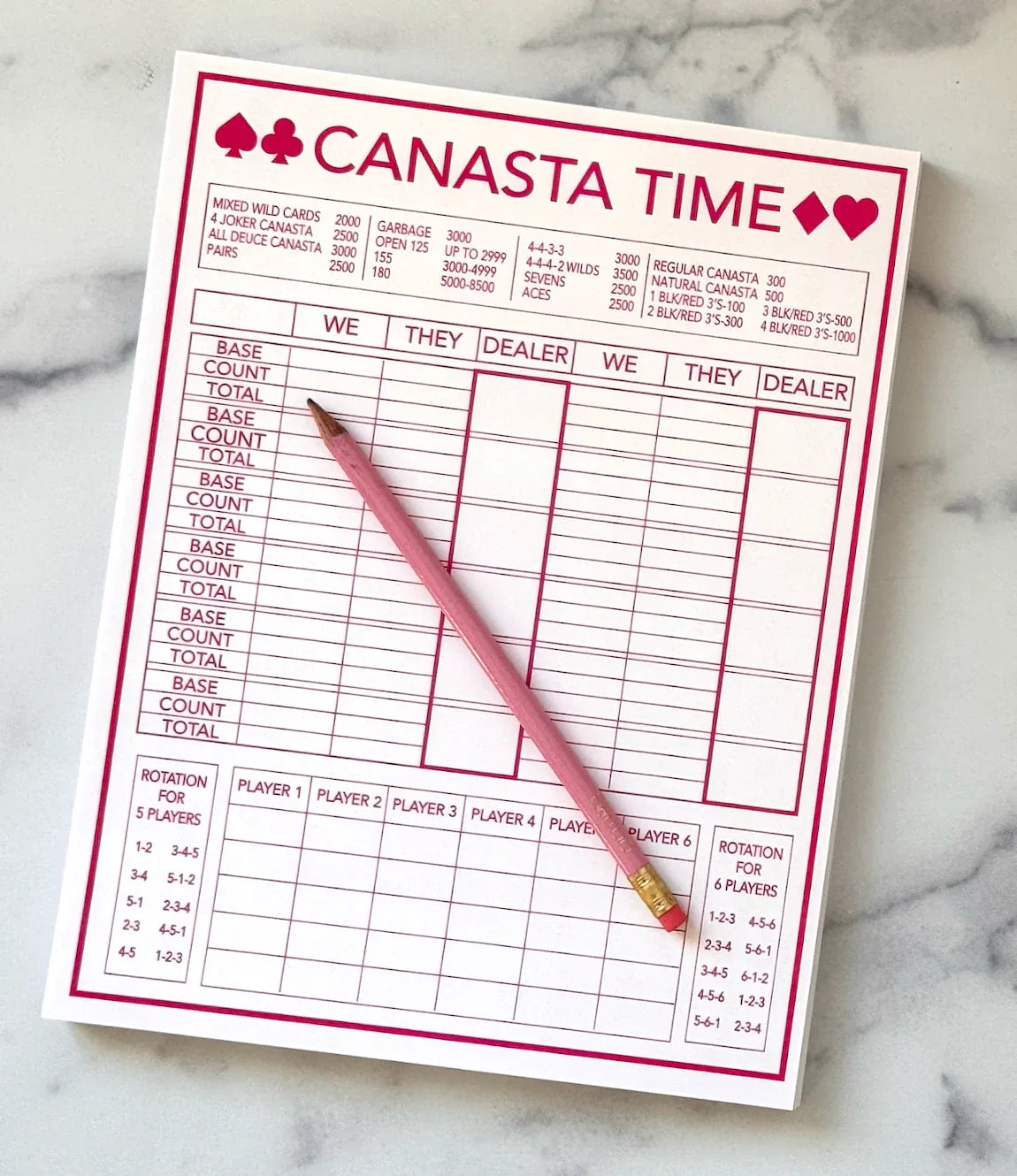 Pink Canasta score sheet with a pink pencil on a marble surface