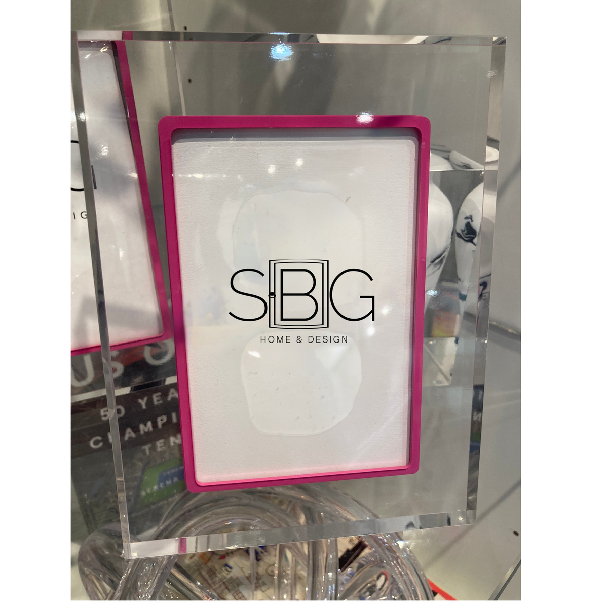 Exuberant Pink Acrylic Picture frame with SBG Home & Design logo on a reflective glass surface