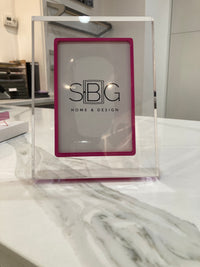 Exuberant Pink Acrylic frame with SBG Home & Design logo on a marble surface