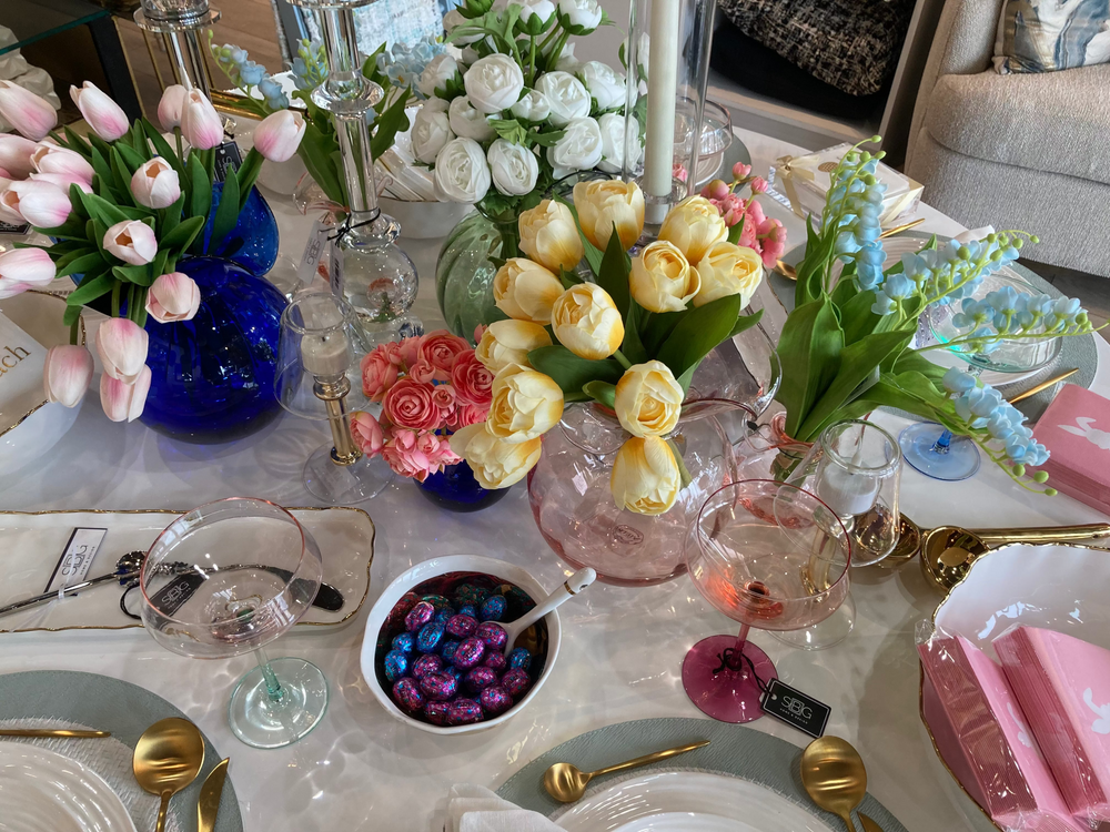 Elegant table setting with flowers, glasses, and silverware on a white tablecloth.